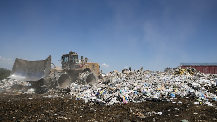 Un camion remblaie des montagnes d'ordures.
