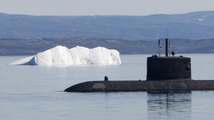 Un sous-marin faisant surface près d'un iceberg.