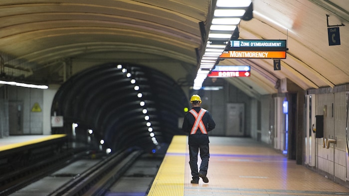 Un employé d’entretien du métro de Montréal marche sur le quai d’une station.