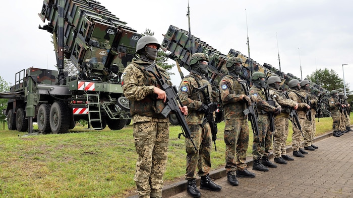 Des militaires en rang devant des systèmes de missiles de défense aérienne.