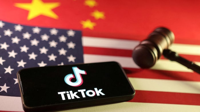 Un téléphone avec le logo de TikTok, un maillet et des drapeaux de la Chine et des États-Unis.