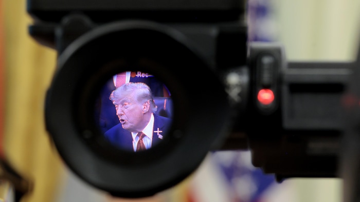 Donald Trump dans le bureau ovale, vu à travers la lentille d'une caméra.