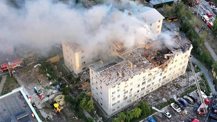 Vue aérienne d'un immeuble en feu, dont une partie du toit est écroulée.
