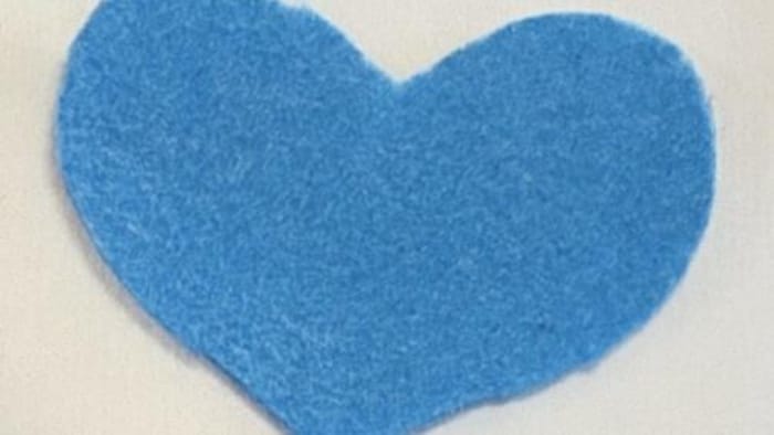 Un cœur bleu découpé dans un morceau de feutre.