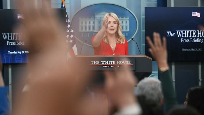 Karoline Leavitt, au lutrin de la Maison-Blanche, pointe vers l'un des journalistes qui lèvent la main.