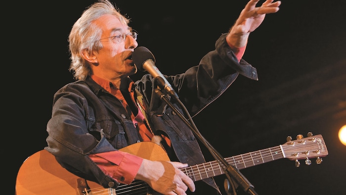 Richard Desjardins avec une guitare en spectacle.
