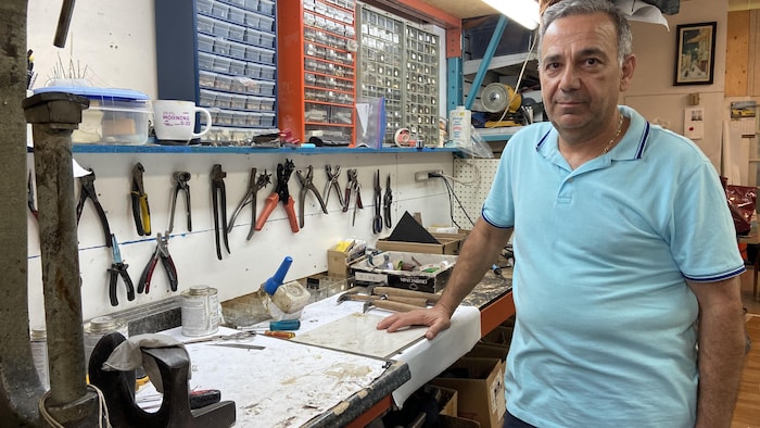 رجل يقف في مشغل نرى فيه معدات تستخدم في إصلاح المنجات الجلدية.