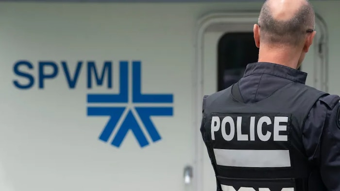 Un policier, de dos, devant un logo du SPVM.
