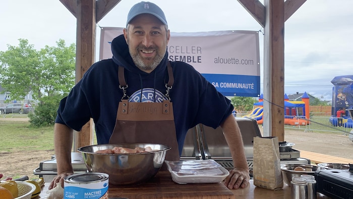 Un cuisinier est derrière un comptoir sur lequel plusieurs aliments sont prêts à être cuisinés. 