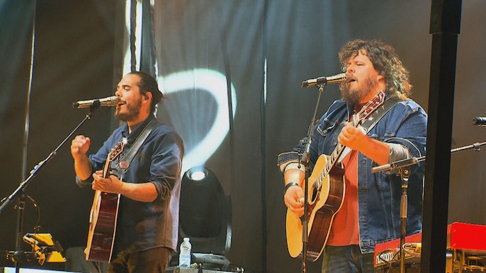 Erik et Sonny Caouette jouant de la guitare et chantant sur scène lors d'un spectacle.