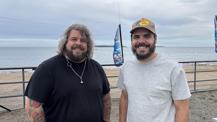 Les membres du duo 2Frères posent tout sourire avec le golfe du Saint-Laurent en arrière-plan.