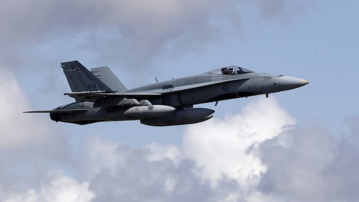 Un avion de chasse CF-18 vole dans les airs. 