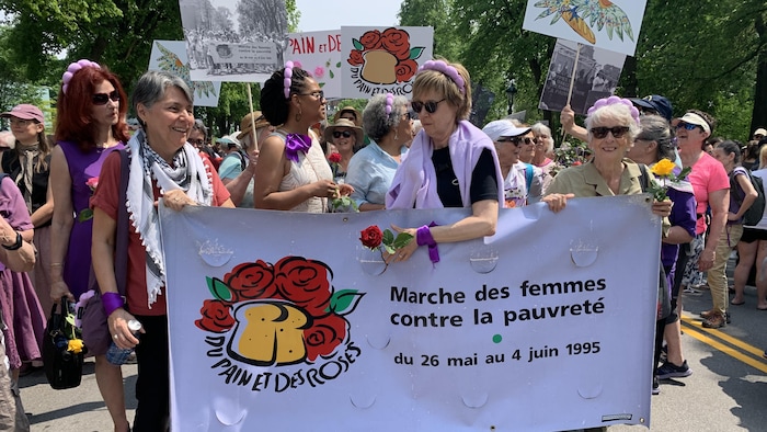 Des dizaines de femmes tiennent une pancarte.