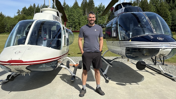 Bastian Fleury devant deux hélicoptères.