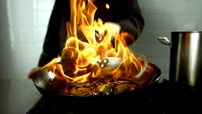 Des légumes sautés enflammés dans un wok.