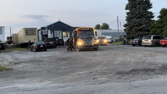 Quelques personnes migrantes montent dans un autobus scolaire.