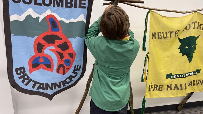 Un enfant accroche des bouts de bois ensemble.