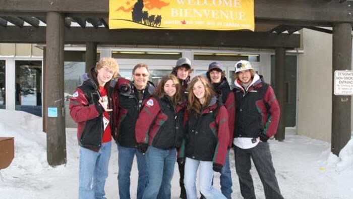 Un groupe de jeune souriant devant une affiche bienvenue