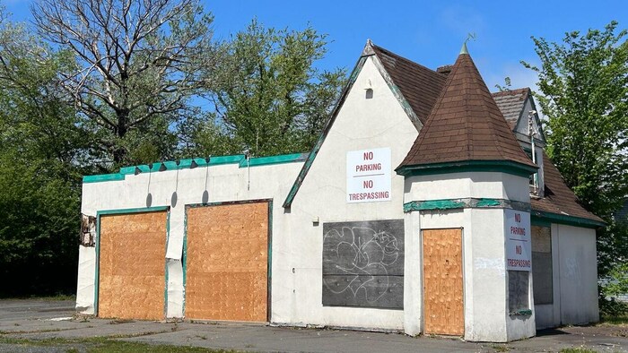 Un petit bâtiment avec une poivrière conique, abandonné, ses portes et fenêtres placardées.