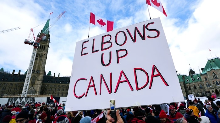 Devant le parlement du Canada, une affiche dit Elbows Up Canada.