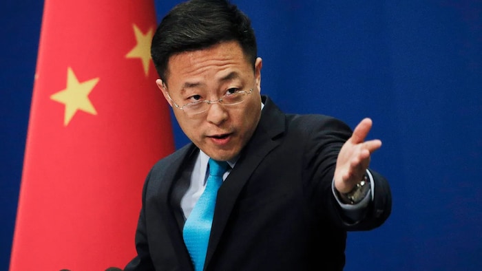 المتحدث باسم وزارة الخارجية الصينية، جاو ليجيان، ماداً ذراعه لإعطاء الكلام لأحد الأشخاص (لا نراه في الصورة).