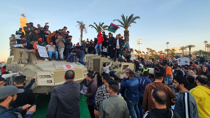 Des hommes et des enfants juchés sur des chars d'assaut agitent des drapeaux libyens dans les rues de Tripoli.