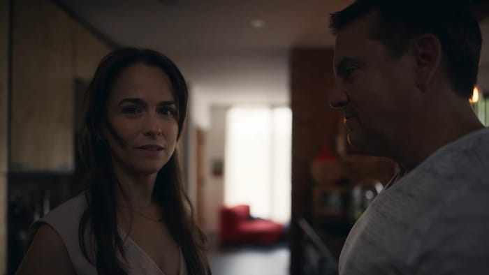 Les deux interprètes se tiennent look à face, debout dans une cuisine de maison. Cathleen Rouleau regarde dans l'objectif de la caméra, alors que Claude Legault regarde l'actrice.