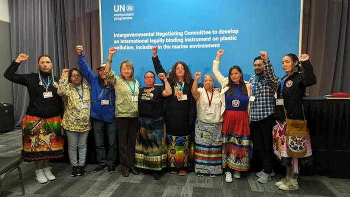 Une dizaine de membres posent, le poing en l'air, devant une affiche de l'ONU.