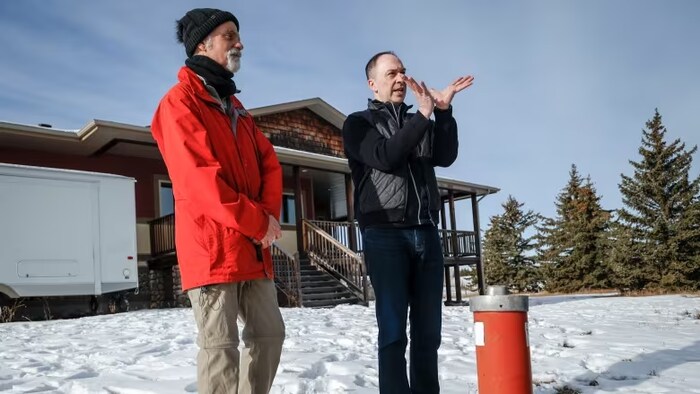 Aaron Goodarzi parle en faisant des gestes de la main avec un autre homme, près d'Okotoks, en Alberta, le 22 février 2024.