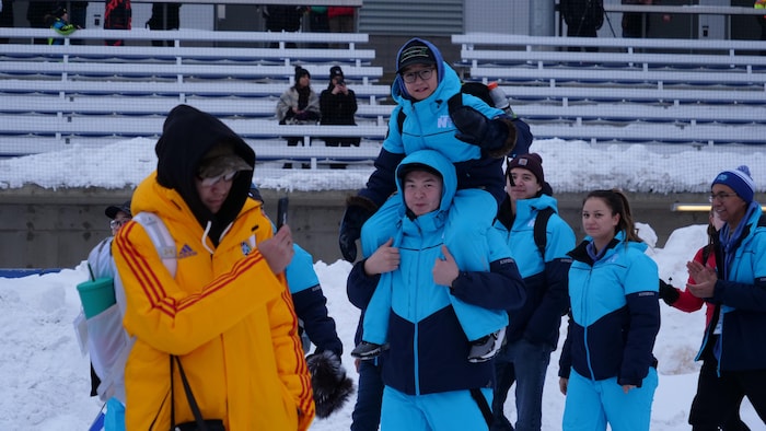 Des membres de la délégation des Territoires du Nord-Ouest marchent, alors qu'un membre de celle du Nunavut prend une photo lors des cérémonies de clôture des Jeux d'hiver de l'Arctique, à Wood Buffalo, en Alberta, le samedi 4 février 2023.