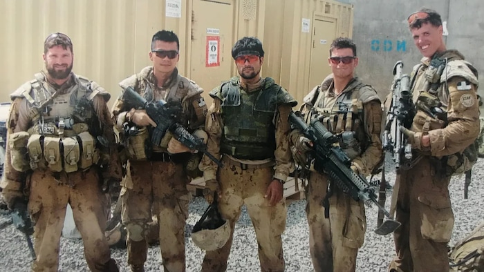 Azizi, centre, is seen with Canadian Forces soldiers. Martin, a long-time friend of the interpreter, is on the far left.