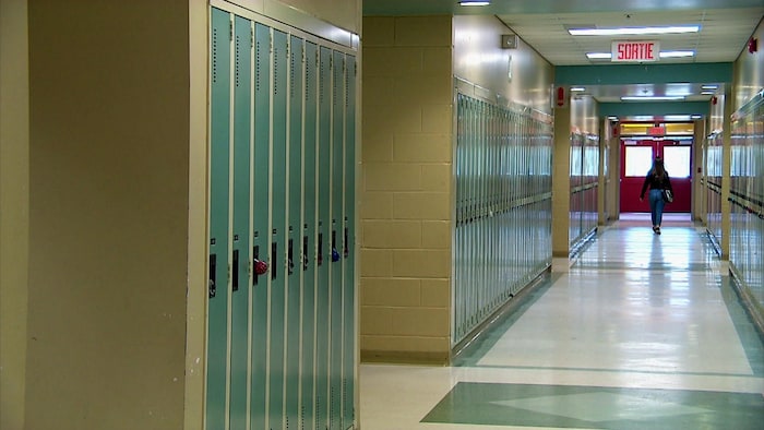 Élève qui marche dans un corridor vers la sortie de l'école.