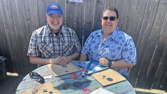 Deux personnes souriantes à une table font de l'artisanat.