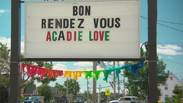 Une affiche aux couleurs de l'arc-en-ciel (drapeau de la fierté) souhaitant un bon Acadie Love à tous. 