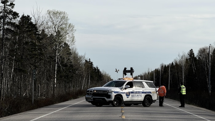 Un véhicule de sécurité bloque la route. Au loin derrière, un avion de la SOPFEU.