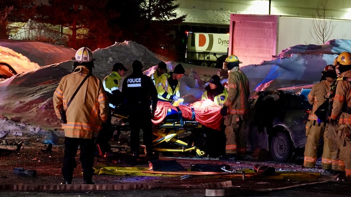 Des pompiers et des policiers autour d'une civière.