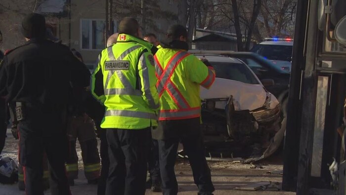 Un capot de voiture endommagé avec du personnel d'urgence à côté, le 21 février 2025 à Winnipeg. 