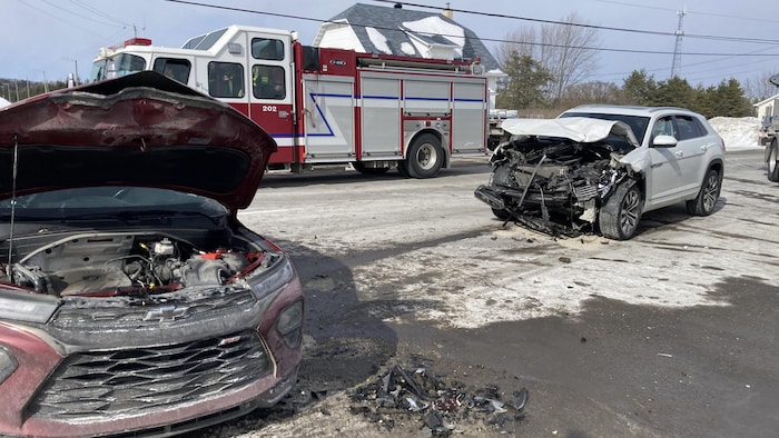 Deux voitures accidentées sont devant un camion de pompiers.