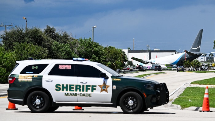 Un véhicule du bureau du shérif de Miami-Dade sur une piste d'atterrissage où se trouve un avion accidenté derrière un cordon de sécurité.
