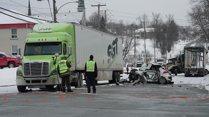 Des agents regardent une voiture accidentée à côté d'un camion