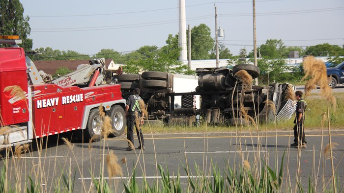 Un camion est couché, des dépanneuses s'affairent autour.