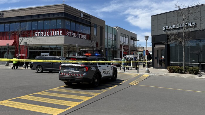 Un véhicule de police et des rubans de police sur le stationnement du centre commercial CF Shops at Don Mills.