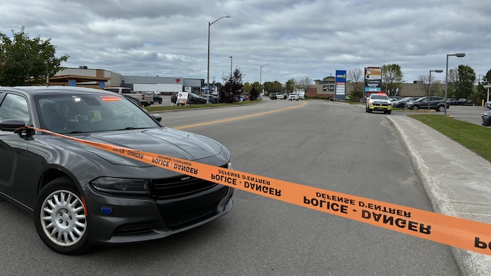 Un ruban de sécurité devant une voiture de police.