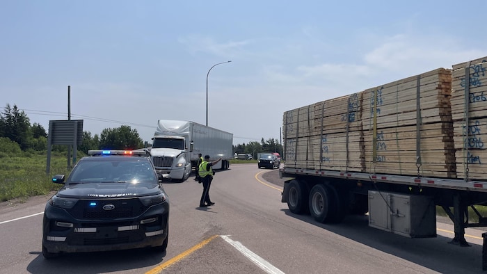 Un véhicule du ministère de la Justice et de la Sécurité publique sur une route et des camions. 