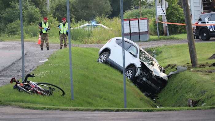 Une voiture accidentée dans un fossé avec un vélo non loin.