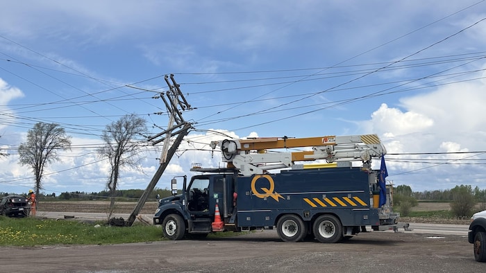 Un véhicule d'Hydro-Québec stationné devant un poteau électrique penché.