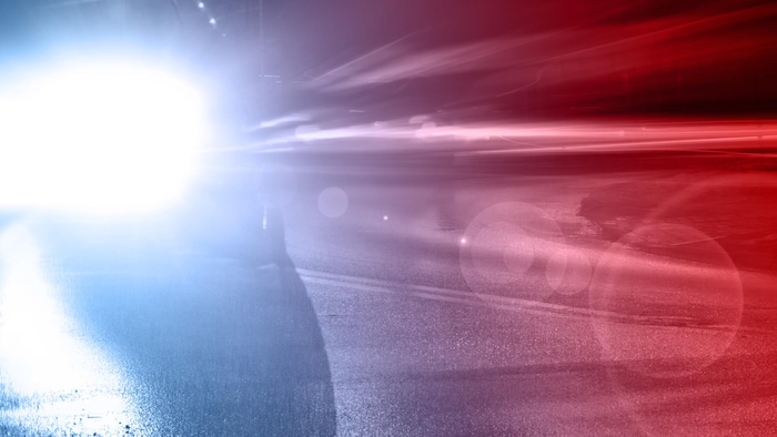 Des lumières de véhicule d'urgence sur une route, la nuit.