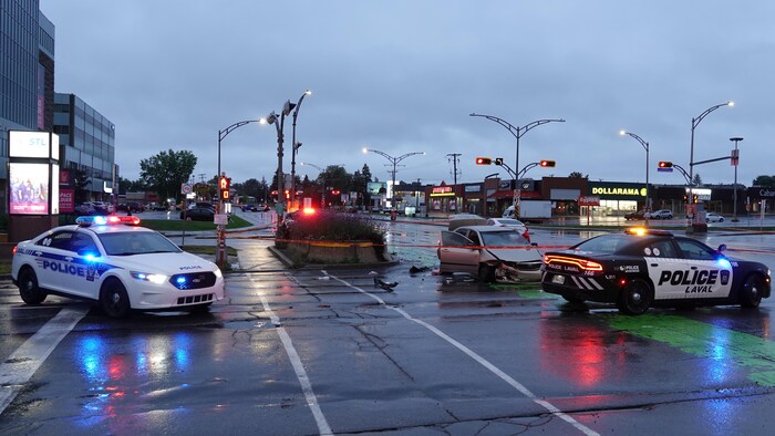 Deux voitures accidentées entourées d'un ruban de sécurité et deux voitures de police.