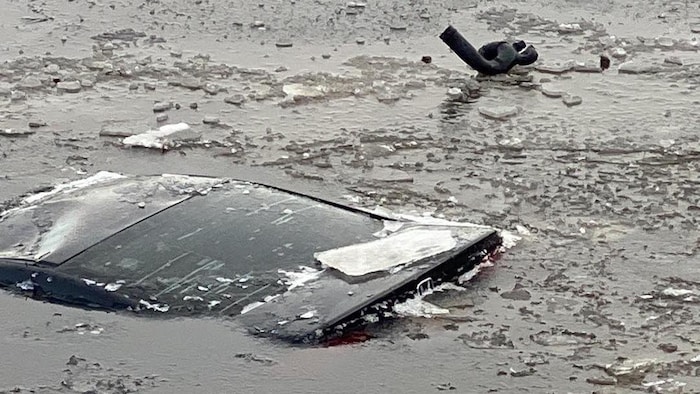 Seul le toit de la voiture est visible dans l'eau dans laquelle des morceaux de glace se sont formés.