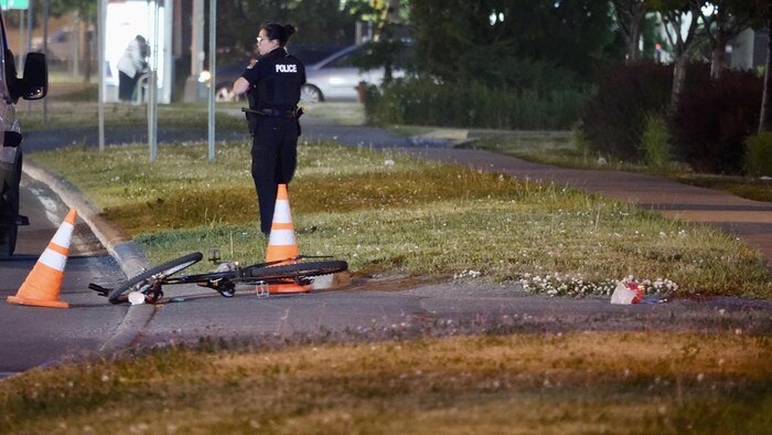 Une policière surveille le vélo, au sol.